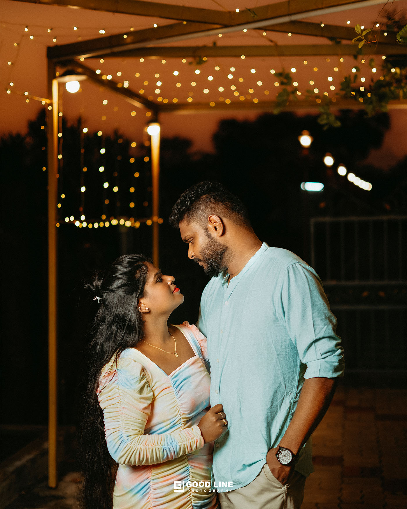 Couple posing outdoors surrounded by greenery